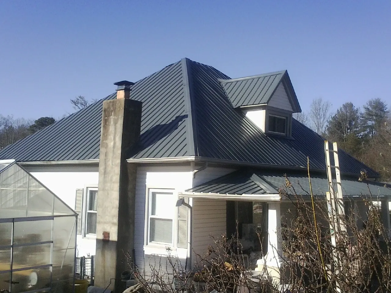 Dark blue standing seam metal roof on a white farmhouse with dormer — Slate & Tile Roof Repair by Roofing Brothers in Sharps