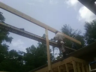 Carpenter setting a ridge beam over a new addition frame — Ice Dam Removal by Roofing Brothers in Sharps