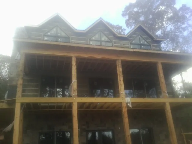 Dormers and porch framing on a large log home under construction — Roof Coating work by our crew in Sharps