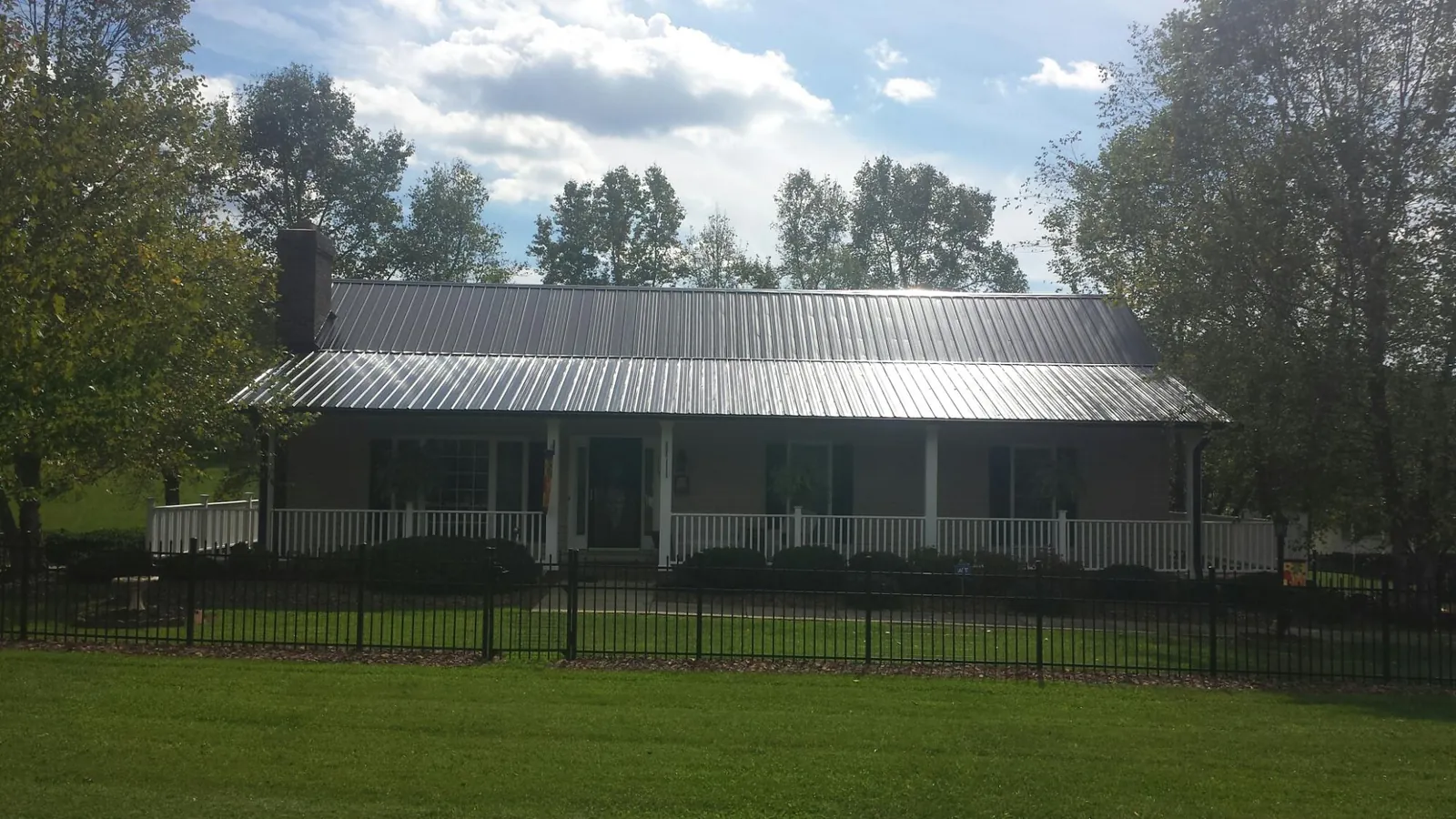 Gray metal roof on a brick ranch with a full width front porch — Gutter Guard Installation work by our crew in Sharps