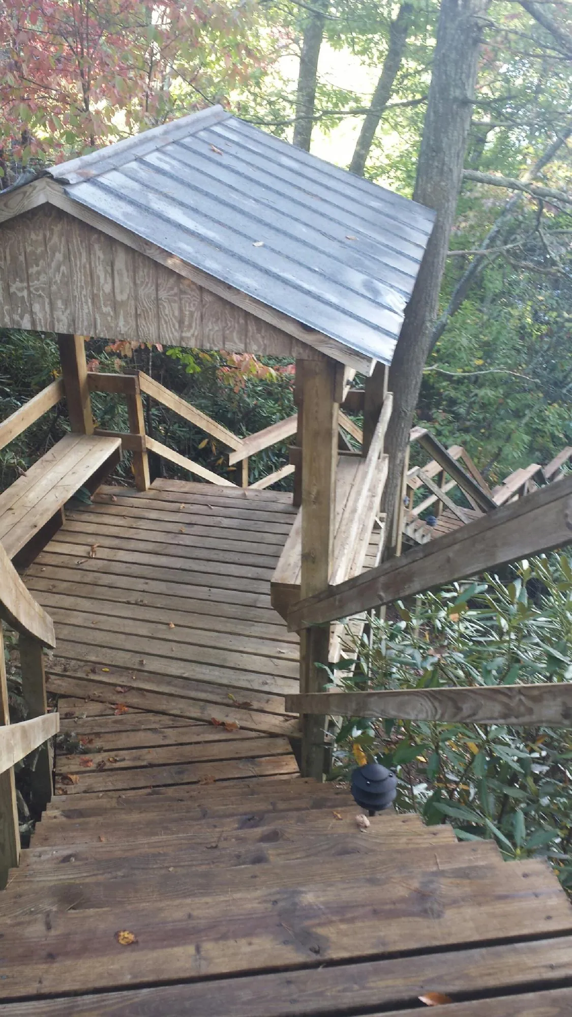 Metal roofed shelter over wooden steps on a wooded walkway — Skylight Repair & Installation work by our crew in Sharps