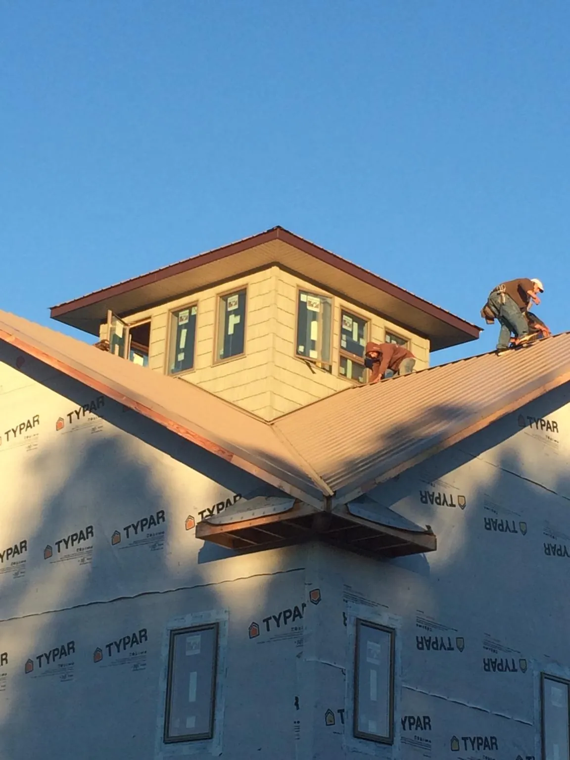 Roofers working around a rooftop cupola on a new metal roof at sunset — Roof Waterproofing in Sharps by Roofing Brothers